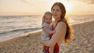 A mother holding her baby on a beach